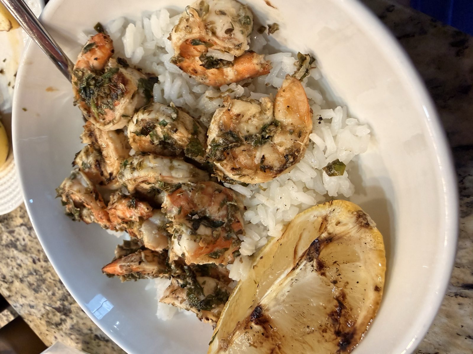 Grilled lemon garlic shrimp served over white rice with a charred lemon half