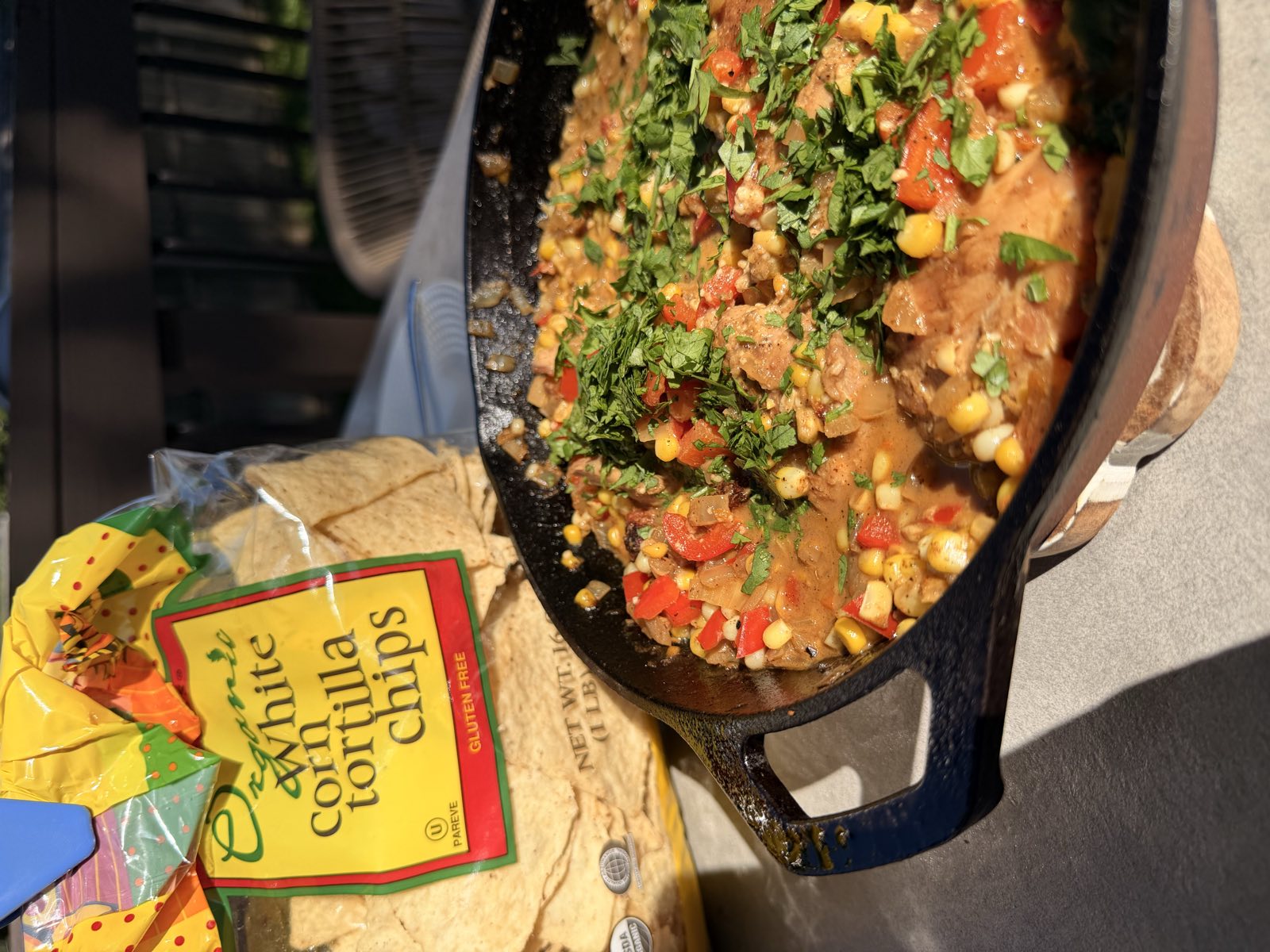 Mexican street corn chicken skillet topped with cilantro, served with a bag of tortilla chips alongside