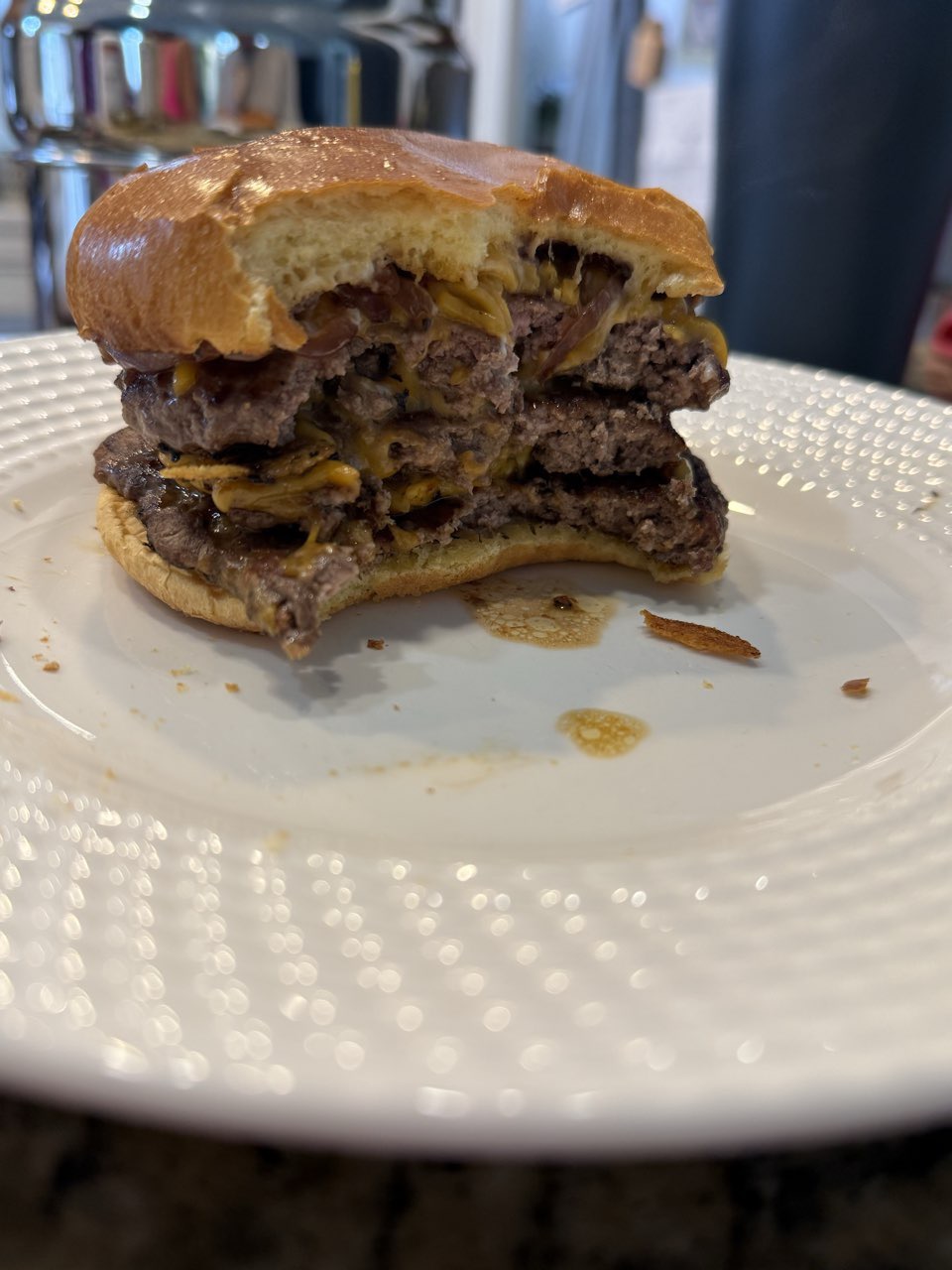 A smash burger cut in half, showing two thin patties with melted cheddar and caramelized onions