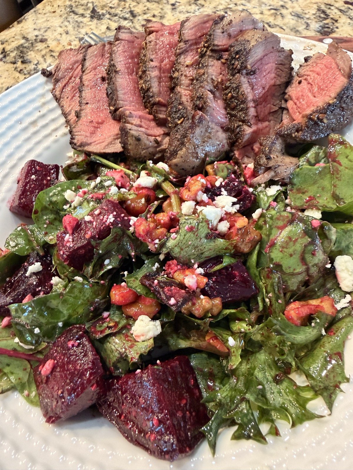 Sliced grilled beef tenderloin with a za'atar crust next to a beet, feta, and walnut salad