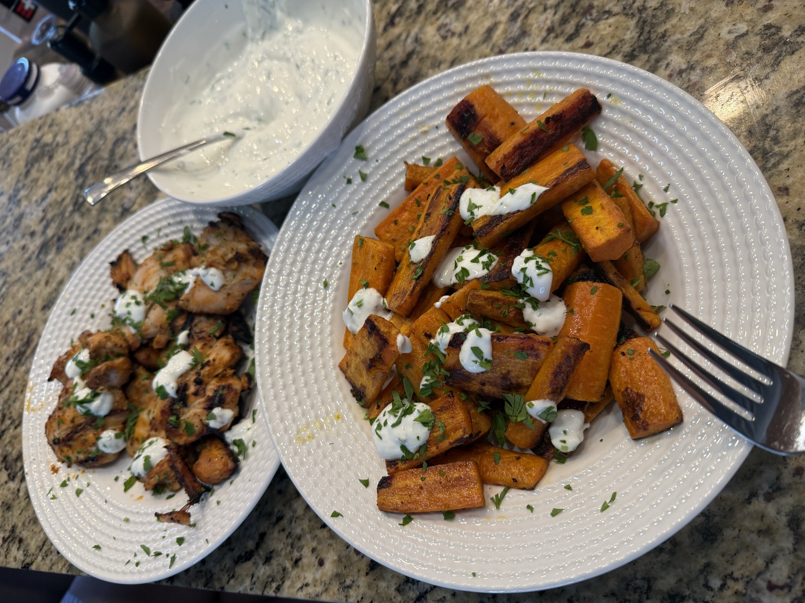 Harissa chicken thighs and roasted carrots plated with garlic yogurt and cilantro