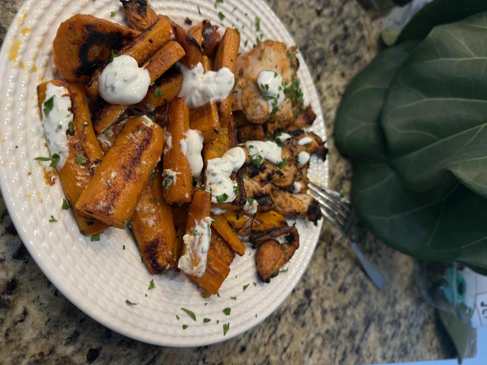 Harissa chicken thighs with roasted carrots and dollops of garlic yogurt on a white plate