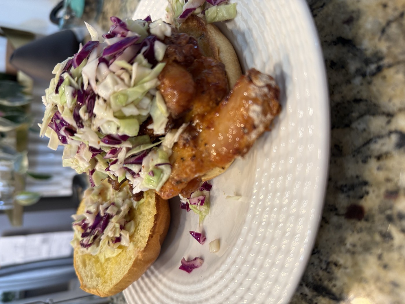 Air-fryer Nashville hot chicken sandwich on a toasted brioche bun, a glazed boneless thigh piled with crispy cabbage slaw on a white plate