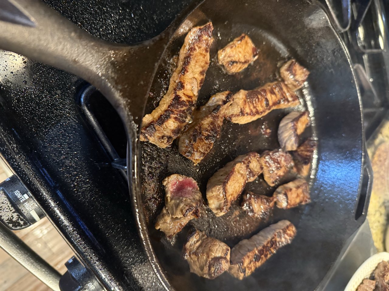 Beef strips searing in a cast iron skillet