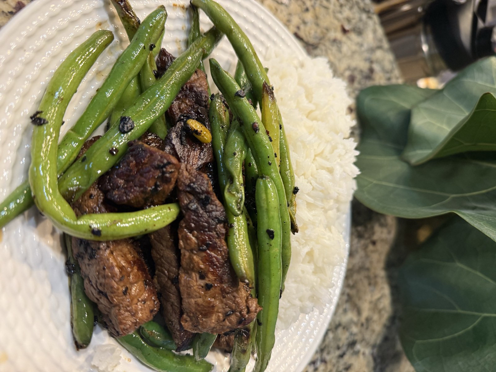Sichuan beef and blistered green beans over white rice on a plate